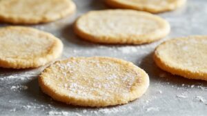 Flat, circular dough pieces sprinkled with flour, prepared for cooking